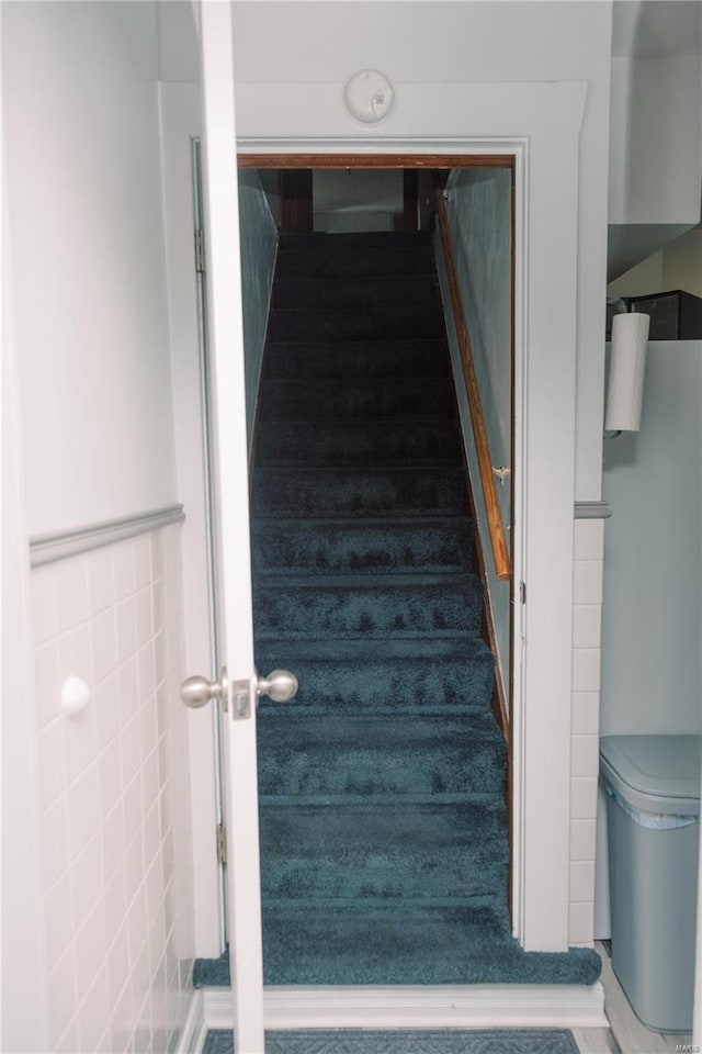 stairs featuring tile walls