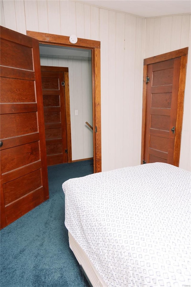 carpeted bedroom featuring wooden walls