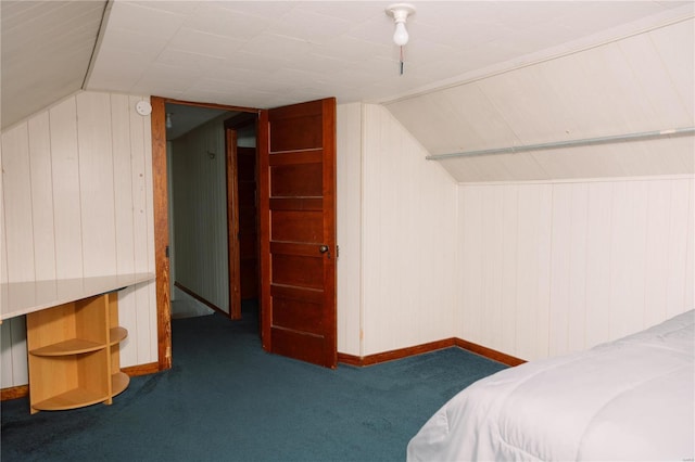 bedroom featuring lofted ceiling, wood walls, and carpet