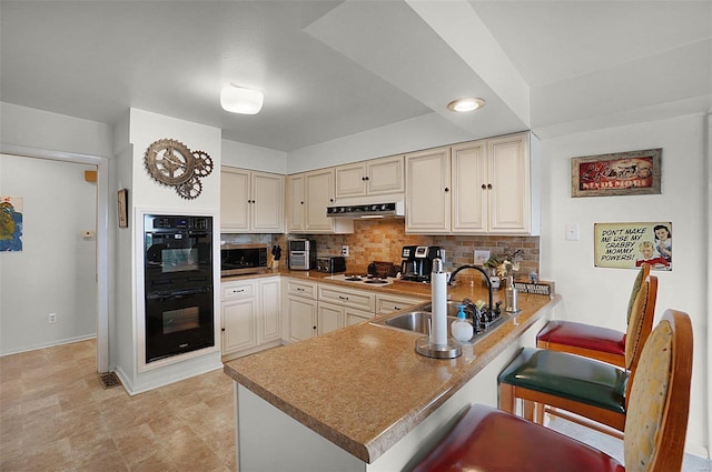 kitchen with tasteful backsplash, sink, double oven, and kitchen peninsula