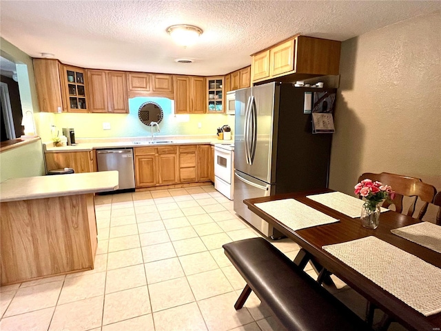 kitchen featuring sink, light tile patterned floors, a textured ceiling, and appliances with stainless steel finishes