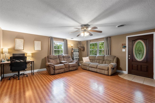 living room featuring ceiling fan, plenty of natural light, and light hardwood / wood-style floors