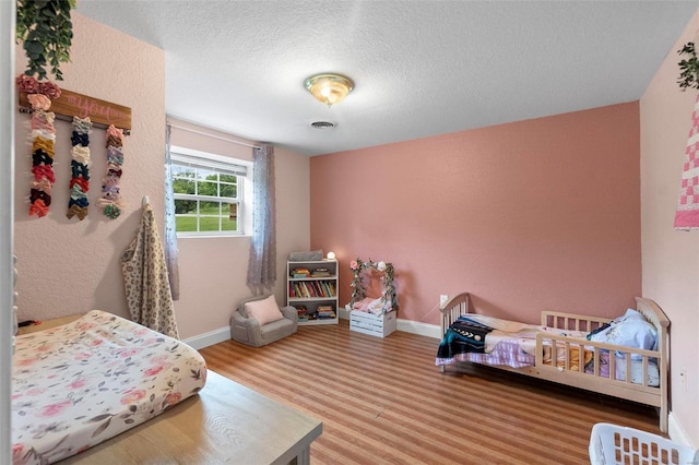 bedroom featuring hardwood / wood-style floors and a textured ceiling