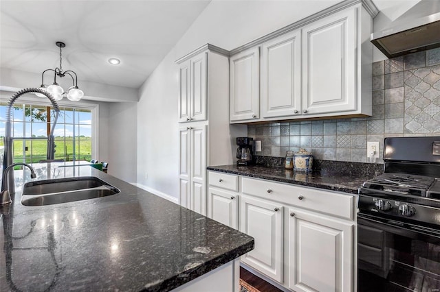 kitchen with black gas stove, dark stone counters, wall chimney exhaust hood, white cabinets, and sink