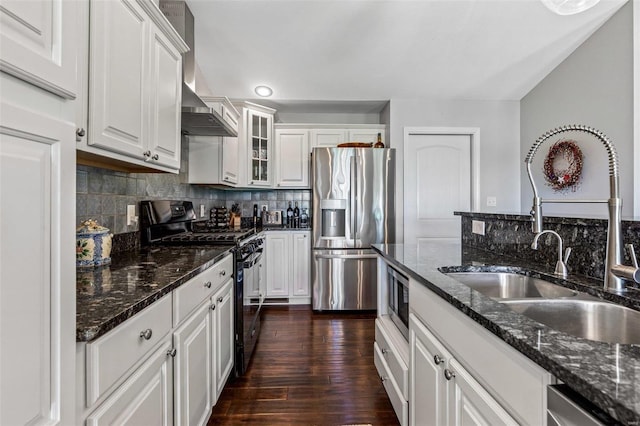 kitchen with dark stone countertops, sink, white cabinetry, dark wood-type flooring, and appliances with stainless steel finishes