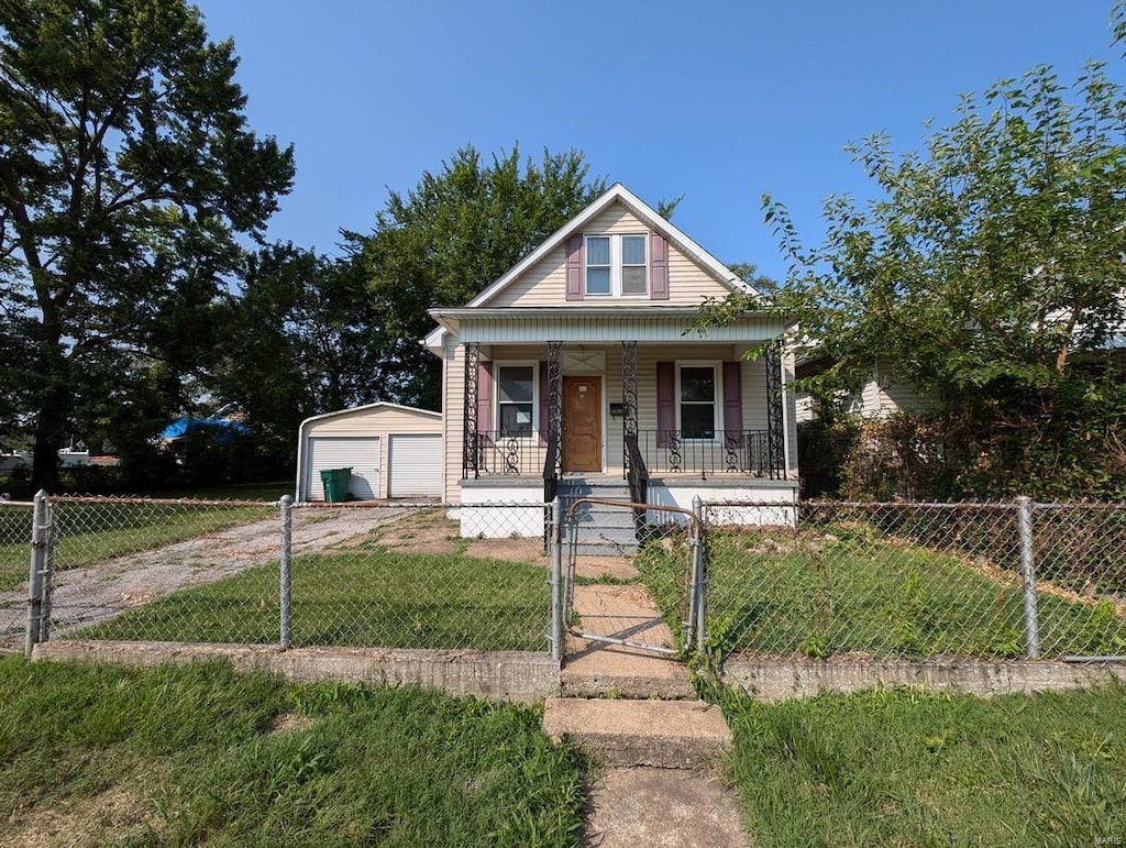 bungalow with an outbuilding, a garage, a front lawn, and covered porch