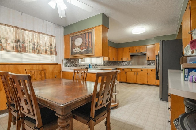 tiled dining space with sink, a textured ceiling, and ceiling fan