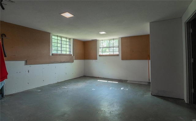 spare room featuring a textured ceiling, concrete flooring, and a healthy amount of sunlight