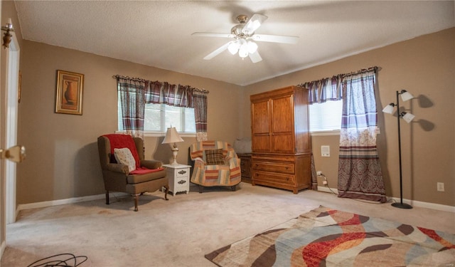 living area featuring light colored carpet, ceiling fan, and plenty of natural light