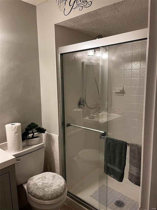 bathroom featuring a shower with door, toilet, and vanity