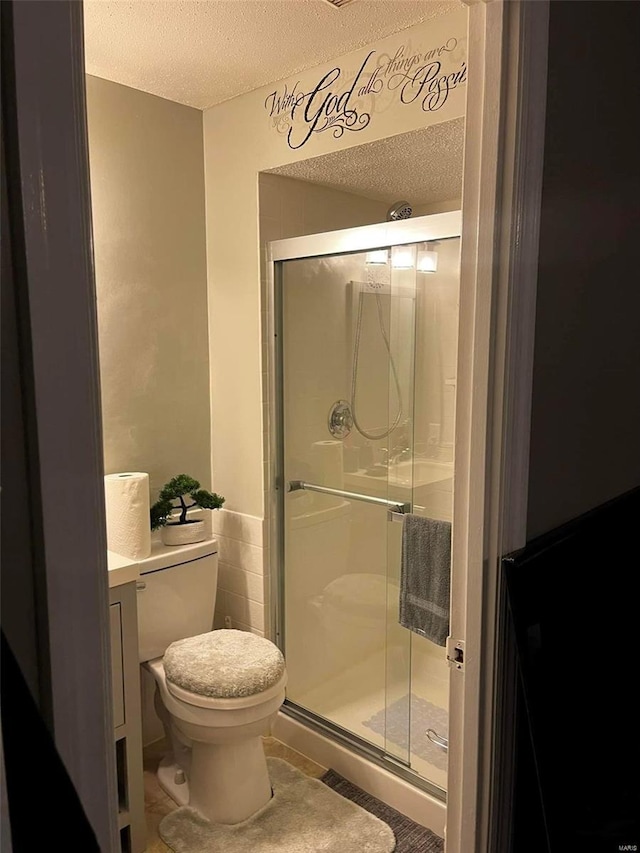 bathroom with an enclosed shower, a textured ceiling, tile patterned floors, toilet, and vanity