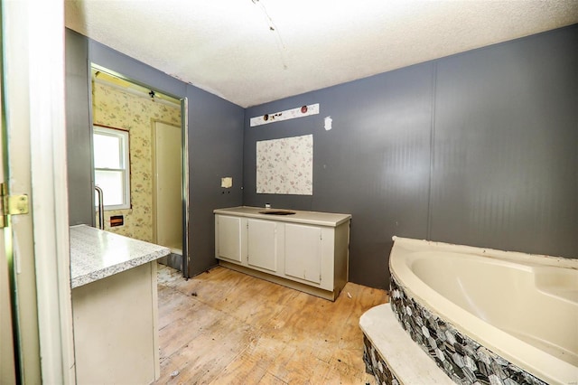 bathroom with vanity, wood-type flooring, a textured ceiling, and a bathing tub