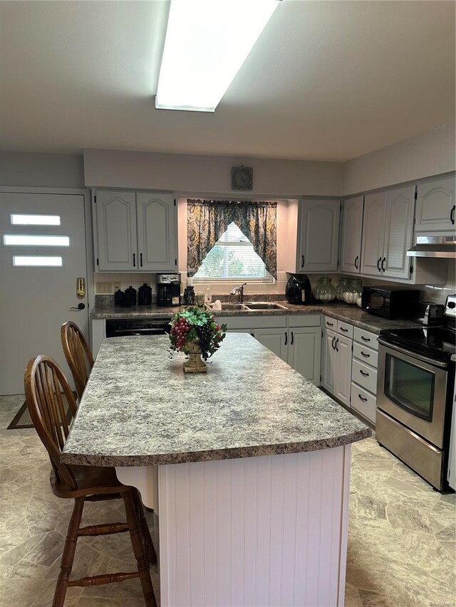 kitchen with a breakfast bar area, stainless steel electric range oven, backsplash, sink, and light tile patterned flooring