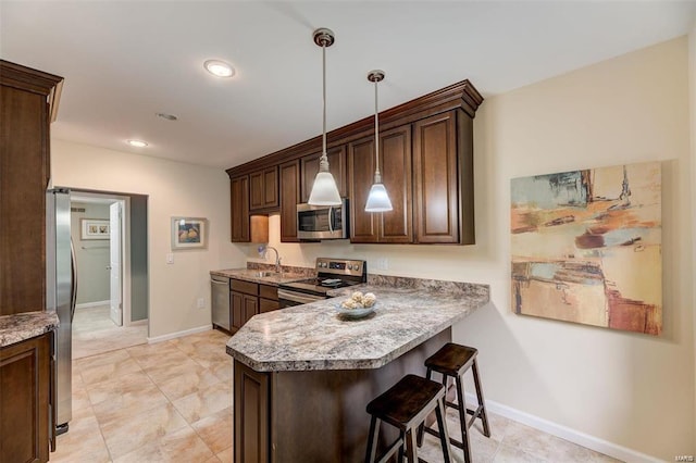 kitchen with pendant lighting, a breakfast bar, kitchen peninsula, light tile patterned flooring, and stainless steel appliances