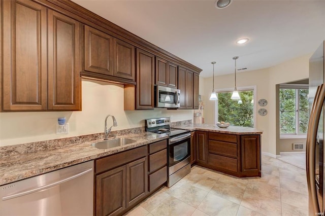 kitchen with light tile patterned flooring, sink, decorative light fixtures, light stone countertops, and stainless steel appliances