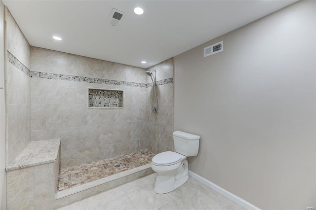 bathroom with tile patterned floors, a tile shower, and toilet