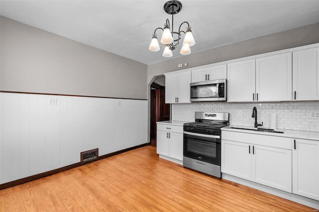 kitchen featuring light hardwood / wood-style floors, hanging light fixtures, appliances with stainless steel finishes, and sink