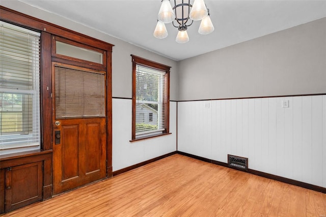 spare room with light wood-type flooring and an inviting chandelier