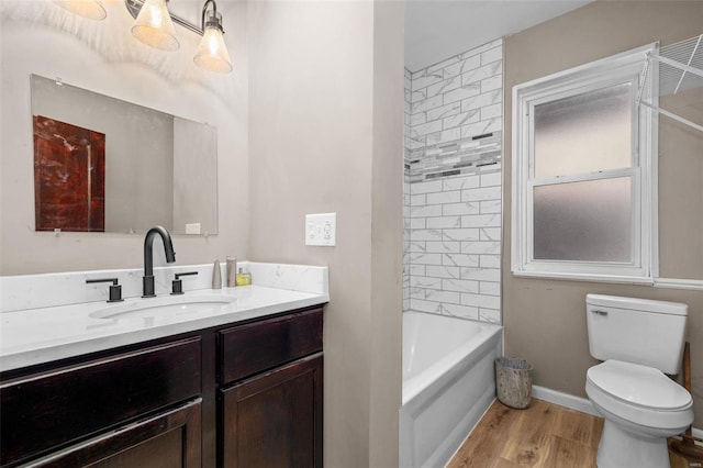 full bathroom featuring vanity, tiled shower / bath, wood-type flooring, and toilet