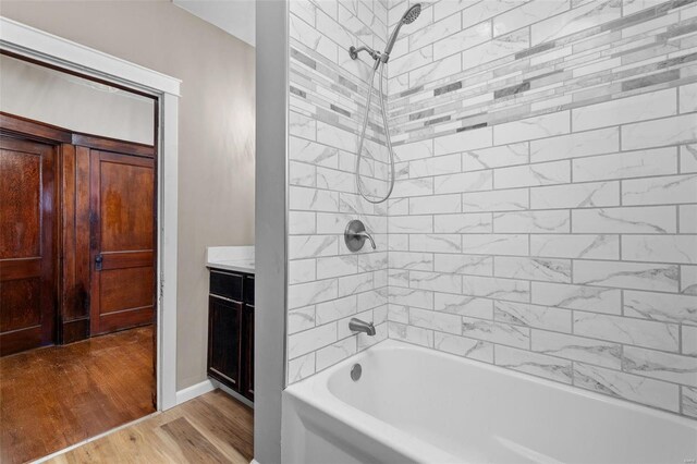 bathroom with vanity, tiled shower / bath combo, and wood-type flooring