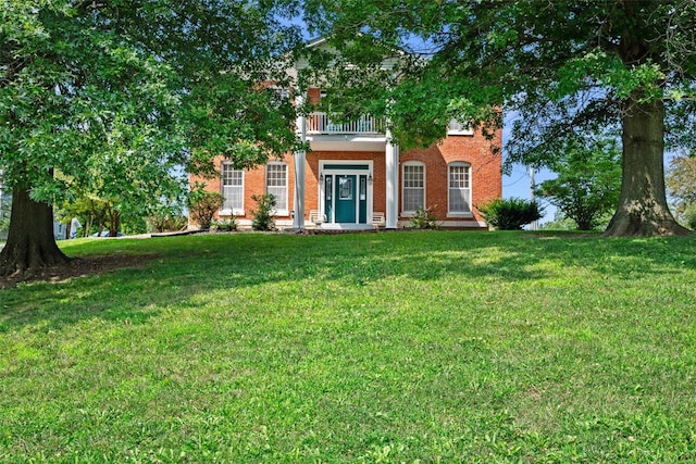 view of front of property with a front yard, brick siding, and a balcony