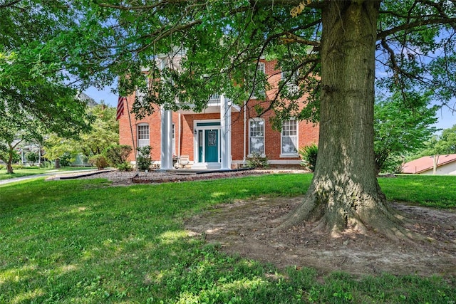 view of front facade with brick siding and a front lawn