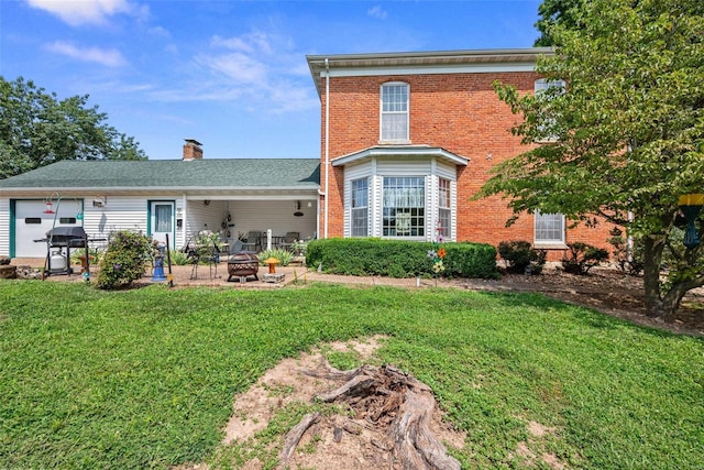 back of property with a fire pit, a lawn, and brick siding