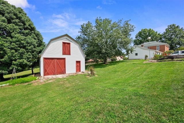 view of yard featuring a barn, driveway, a detached garage, and an outbuilding