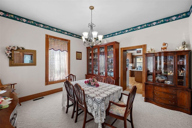 dining area featuring baseboards, light colored carpet, visible vents, and a notable chandelier