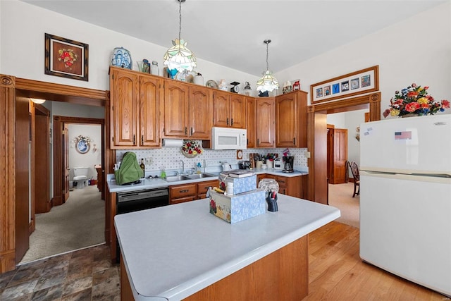 kitchen featuring white appliances, pendant lighting, light countertops, and brown cabinetry