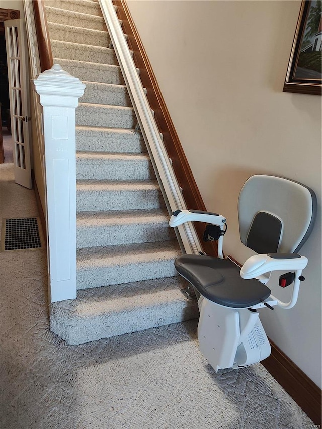 stairway featuring baseboards and visible vents