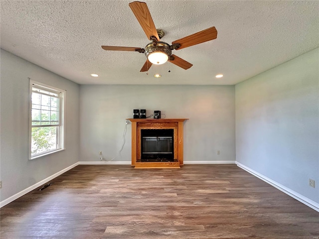 unfurnished living room with ceiling fan, a textured ceiling, and dark hardwood / wood-style flooring