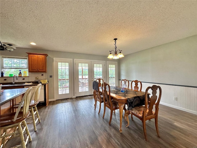 dining space featuring a healthy amount of sunlight, dark wood-type flooring, sink, and a notable chandelier