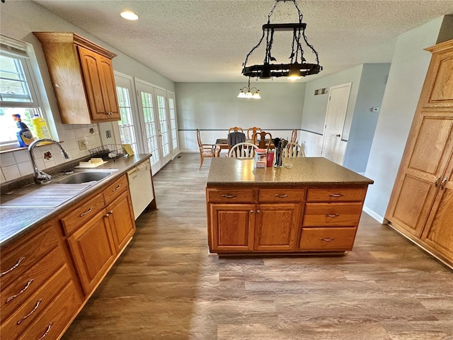 kitchen with hardwood / wood-style flooring, sink, white dishwasher, and decorative light fixtures