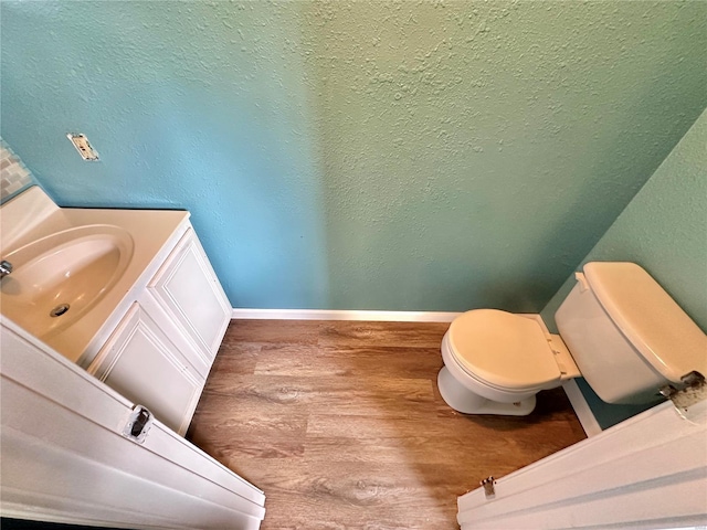 bathroom with wood-type flooring, toilet, and vanity