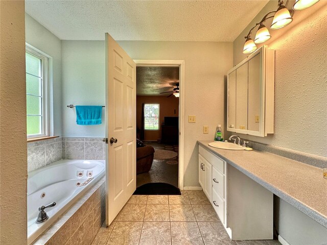 bathroom featuring vanity, a relaxing tiled tub, tile patterned floors, and a textured ceiling