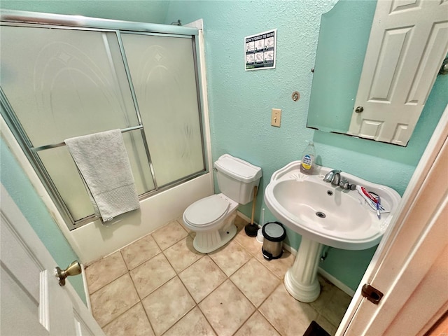 full bathroom featuring sink, tile patterned floors, toilet, and combined bath / shower with glass door