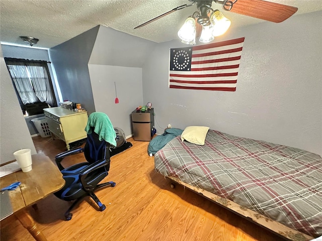 bedroom with hardwood / wood-style flooring, ceiling fan, vaulted ceiling, and a textured ceiling