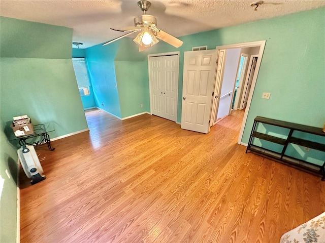 unfurnished bedroom with ceiling fan, a closet, a textured ceiling, and light wood-type flooring