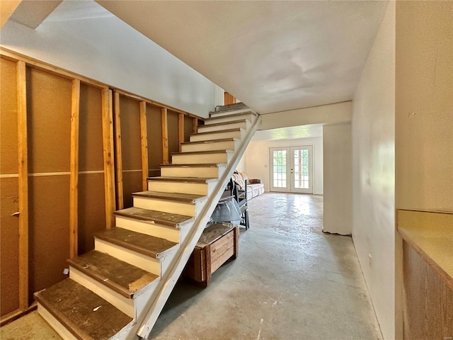 stairway with french doors and concrete floors