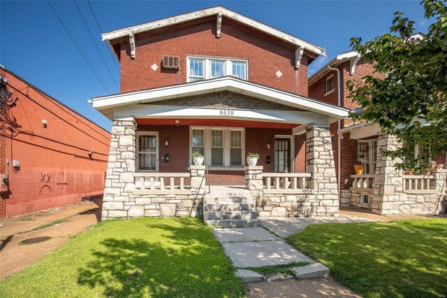 view of front facade with a wall mounted AC, a porch, and a front lawn