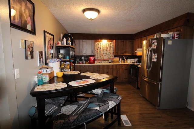 kitchen featuring dark wood-type flooring, black electric range, stainless steel refrigerator, and a textured ceiling