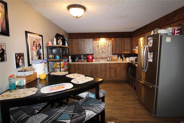 kitchen featuring a textured ceiling, dark hardwood / wood-style flooring, black electric range, and stainless steel refrigerator