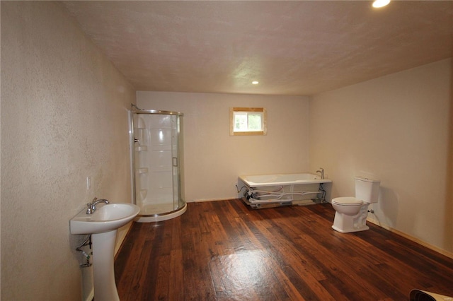 bathroom featuring plus walk in shower, hardwood / wood-style floors, and toilet