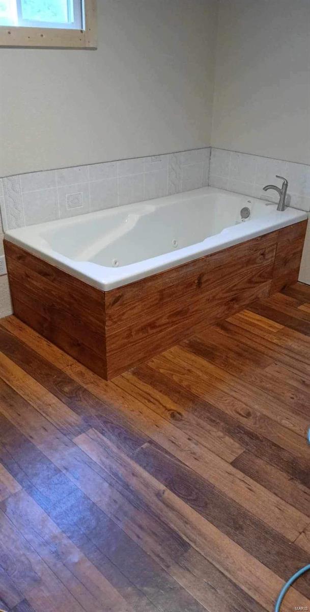 bathroom with hardwood / wood-style floors and tiled bath