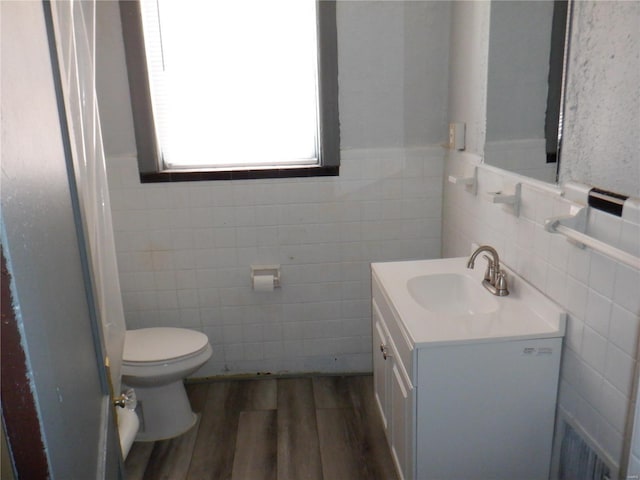 bathroom with hardwood / wood-style flooring, vanity, toilet, and tile walls