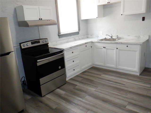 kitchen with sink, stainless steel range with electric stovetop, white cabinets, and refrigerator