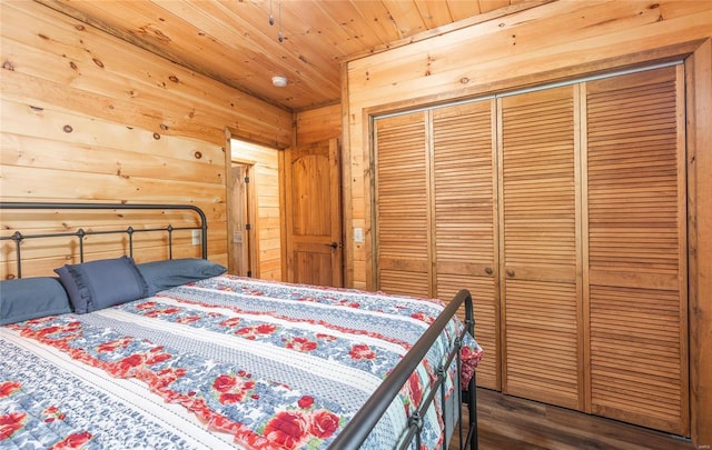 bedroom featuring wood ceiling, wooden walls, a closet, and dark wood-type flooring