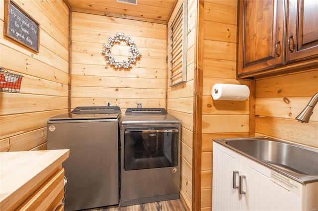 laundry room featuring cabinets, washer and dryer, sink, and wooden walls