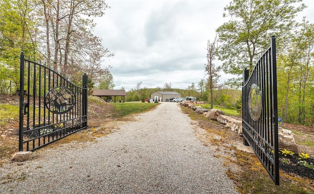 view of road with a gate, gravel driveway, and a gated entry